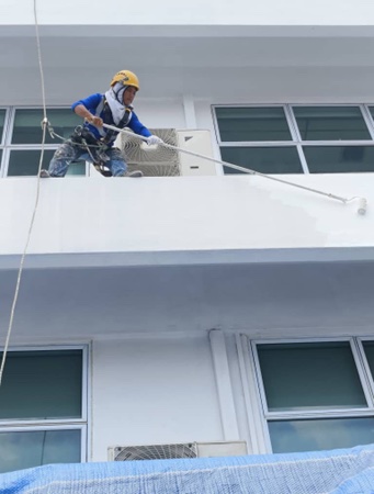 Rope access painter applying external finish on building facade